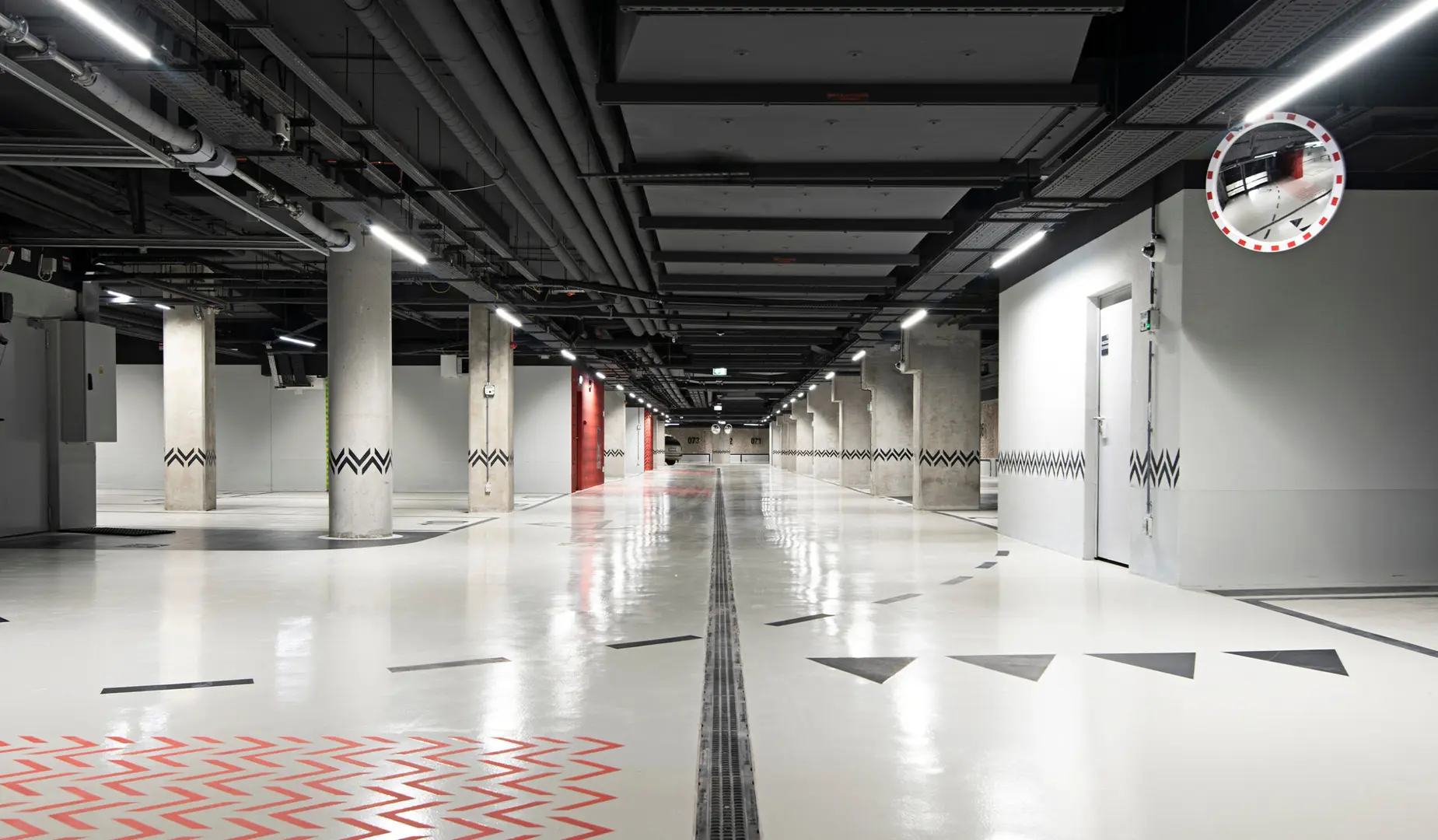 Tiefgarage mit Betonstützen und durchgehenden Lichtleisten an der Decke